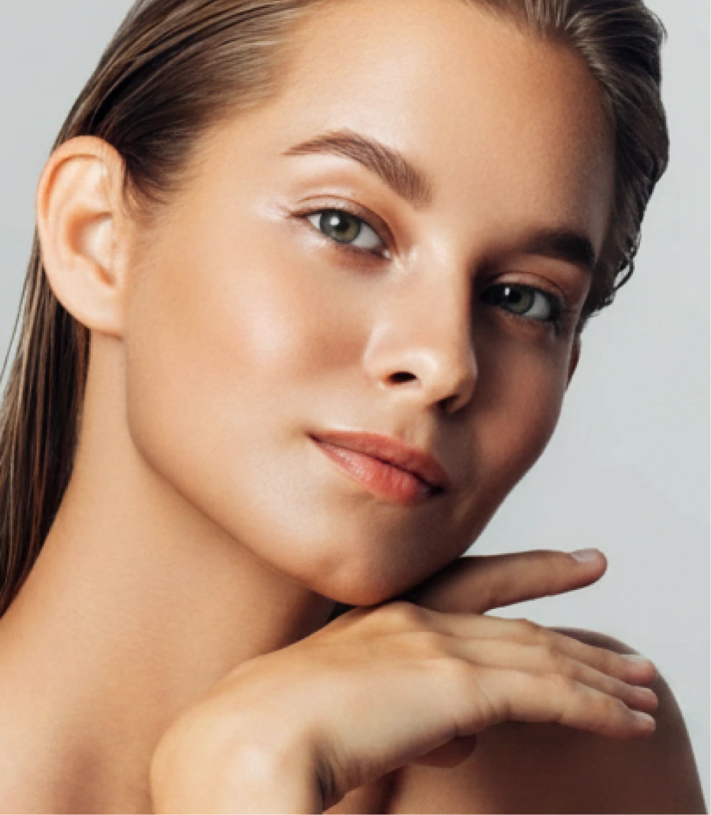 Woman with clear skin touching her face against a neutral background